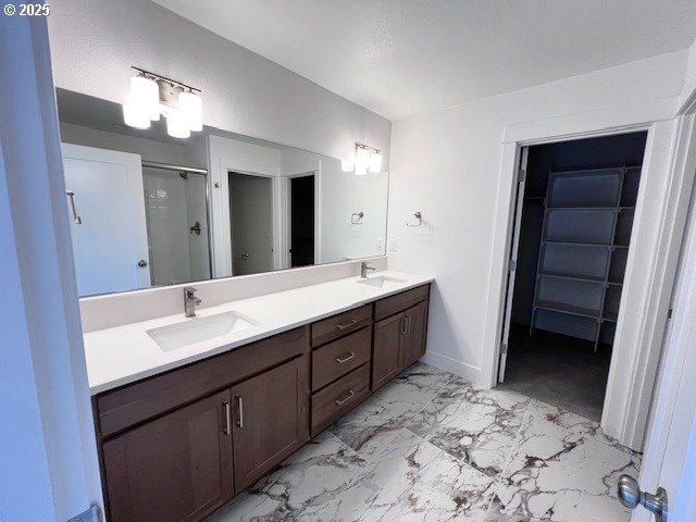 bathroom featuring marble finish floors, a stall shower, and double vanity