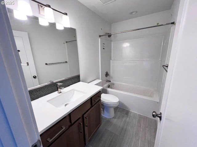 bathroom featuring toilet, vanity, shower / washtub combination, and wood finished floors