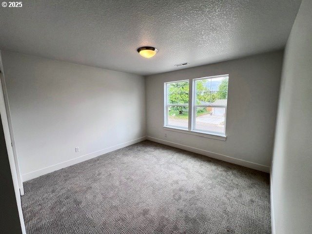 carpeted empty room with baseboards and a textured ceiling