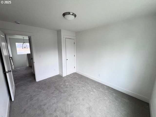 unfurnished bedroom featuring dark carpet and baseboards