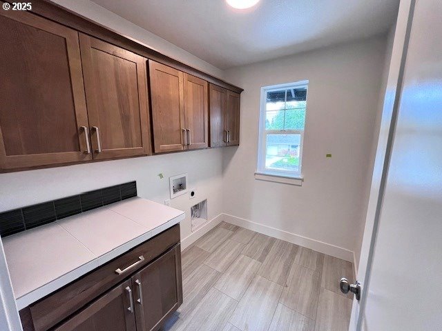 washroom with cabinet space, hookup for a washing machine, electric dryer hookup, baseboards, and light wood finished floors