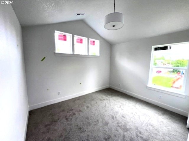 spare room featuring carpet flooring, lofted ceiling, and baseboards