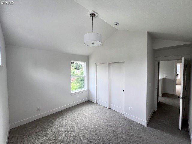 unfurnished bedroom with baseboards, carpet flooring, a closet, and high vaulted ceiling