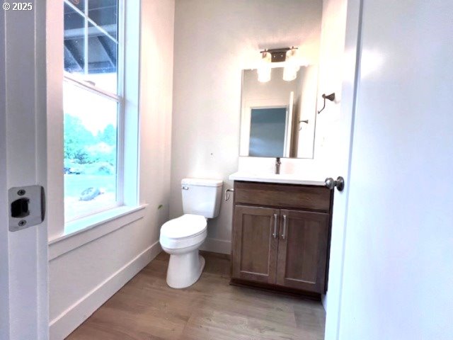 bathroom featuring toilet, vanity, wood finished floors, and baseboards
