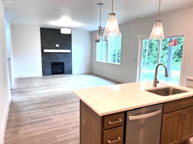 kitchen with a sink, dishwasher, light wood-style floors, light countertops, and pendant lighting