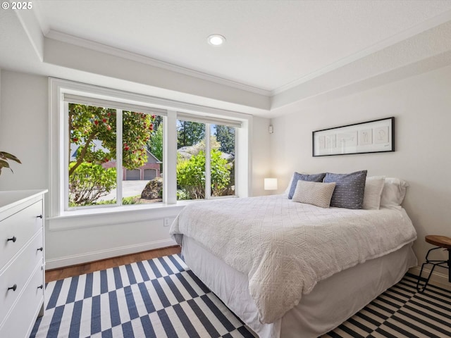 bedroom with multiple windows, ornamental molding, wood finished floors, recessed lighting, and a tray ceiling
