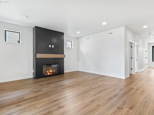unfurnished living room with recessed lighting, a fireplace, light wood-style flooring, and baseboards