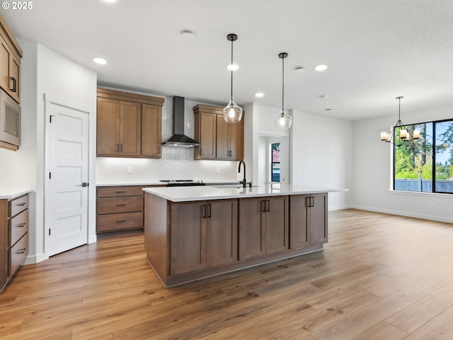 kitchen featuring wall chimney range hood, recessed lighting, light wood-type flooring, and a sink
