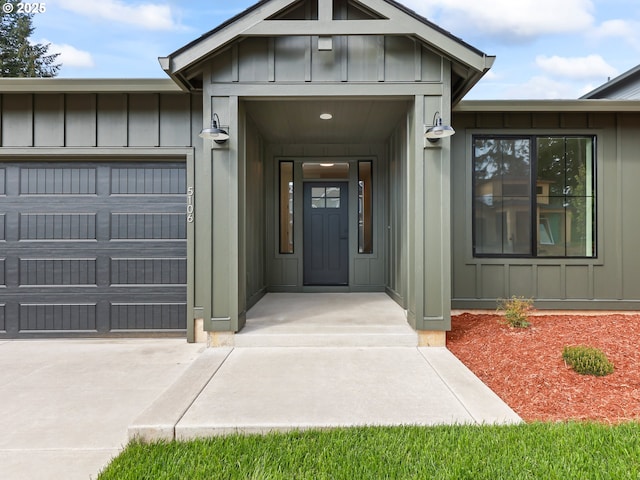 property entrance with board and batten siding, a garage, and concrete driveway