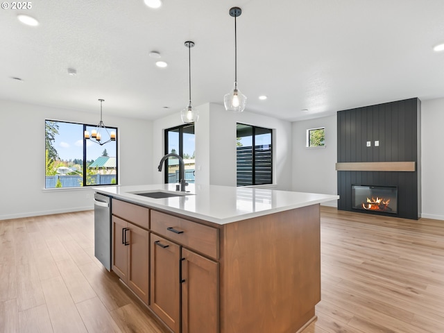 kitchen featuring a sink, a large fireplace, light countertops, and light wood finished floors