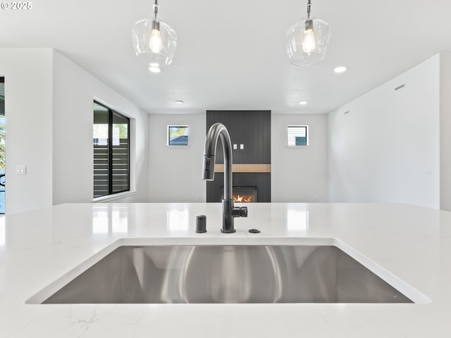 room details featuring a fireplace, pendant lighting, light countertops, and a sink