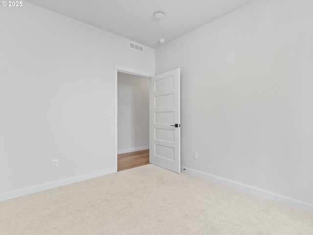 unfurnished room with carpet flooring, visible vents, and baseboards
