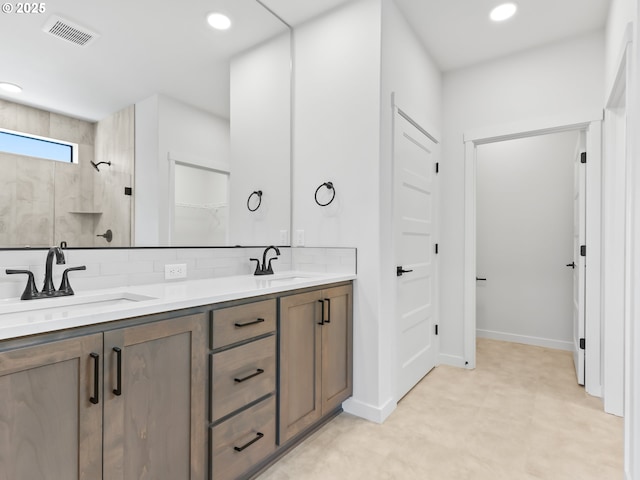 full bathroom featuring a sink, visible vents, a tile shower, and double vanity