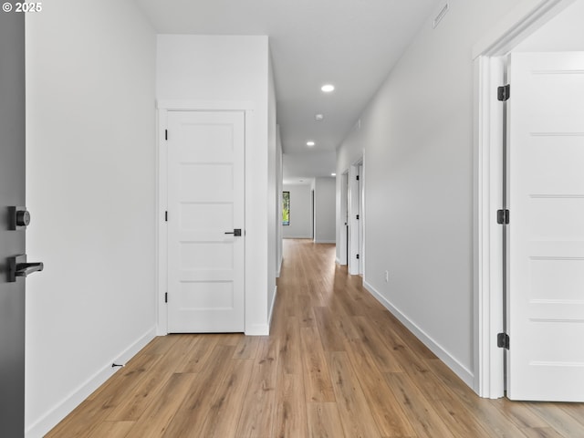 hallway with light wood finished floors, baseboards, and recessed lighting