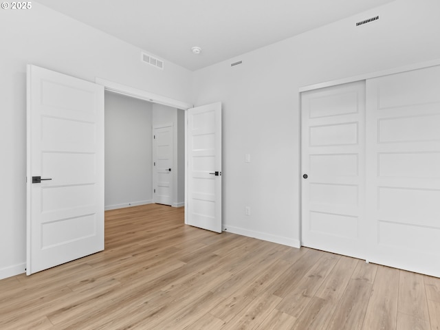 unfurnished bedroom featuring light wood-style flooring, baseboards, and visible vents