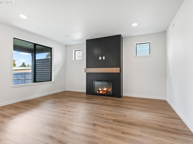 unfurnished living room featuring recessed lighting, a fireplace, light wood-style flooring, and baseboards