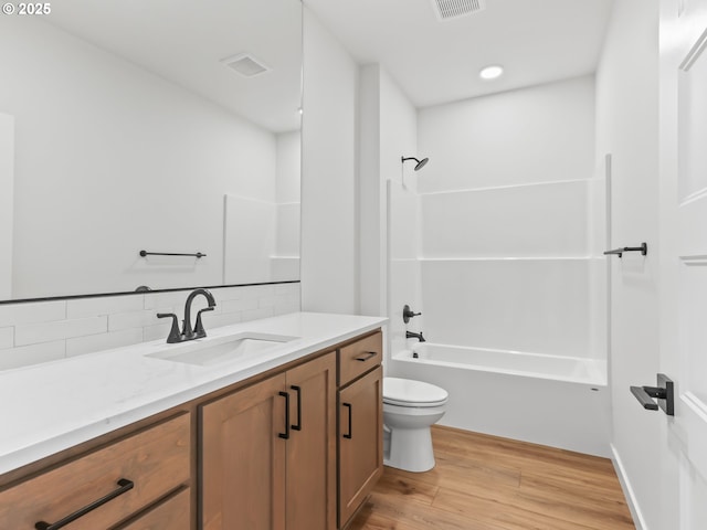 full bath featuring bathing tub / shower combination, vanity, toilet, wood finished floors, and backsplash