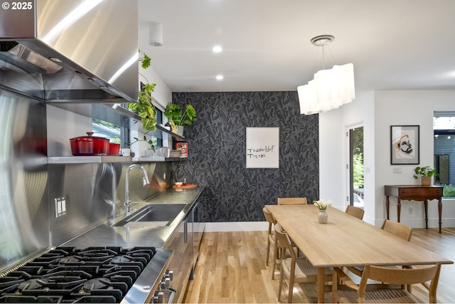 3419 SE Woodward St, Portland, OR 97202 - kitchen featuring an accent wall, wall chimney exhaust hood, wood finished floors, wallpapered walls, and stainless steel countertops