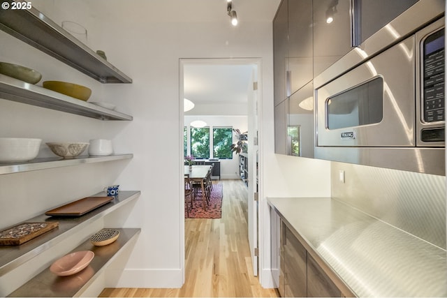 3419 SE Woodward St, Portland, OR 97202 - kitchen featuring stainless steel microwave, stainless steel countertops, light wood-style floors, modern cabinets, and open shelves