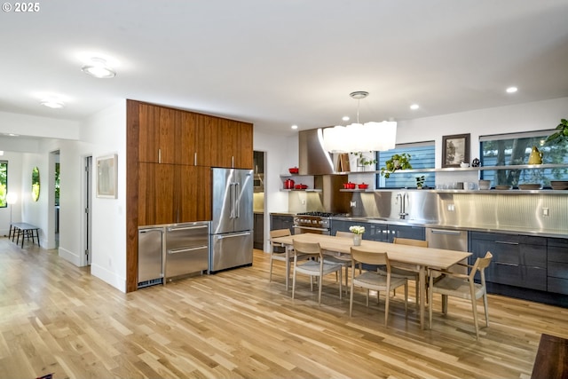 3419 SE Woodward St, Portland, OR 97202 - kitchen featuring stainless steel countertops, premium appliances, range hood, modern cabinets, and brown cabinets