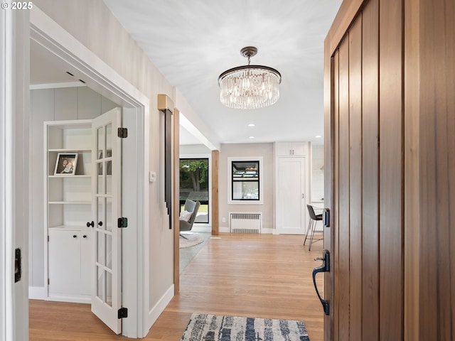 3440 SW 100th Ave, Portland, OR 97225 - hallway with radiator, light wood-style flooring, and a chandelier