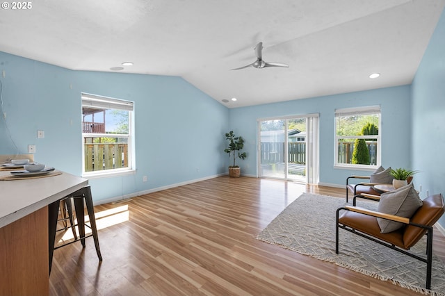 living area featuring visible vents, lofted ceiling, light wood-style floors, baseboards, and a ceiling fan