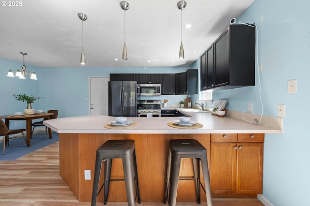 kitchen featuring light wood-style floors, light countertops, a sink, and appliances with stainless steel finishes