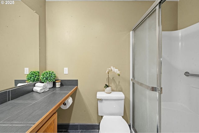 full bath featuring vanity, tile patterned flooring, toilet, baseboards, and a stall shower