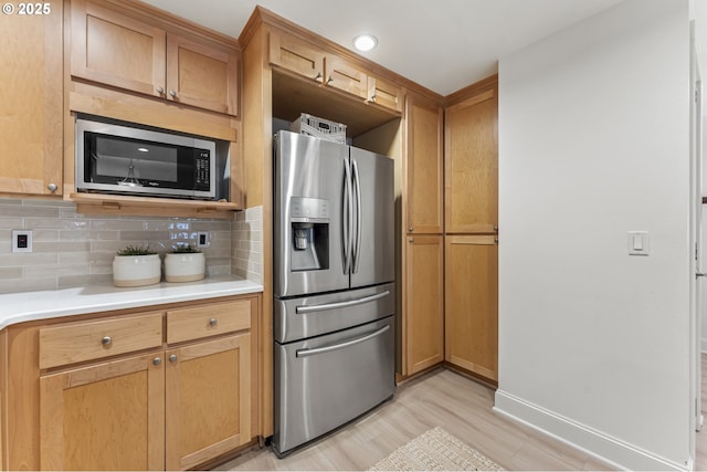 kitchen with decorative backsplash, light wood-type flooring, and stainless steel appliances