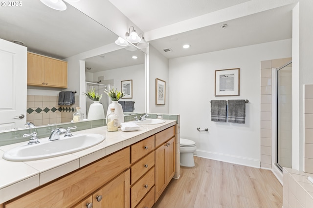 bathroom featuring wood-type flooring, vanity, toilet, and a shower with door