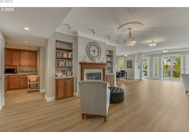 living room featuring built in shelves, light hardwood / wood-style floors, and crown molding