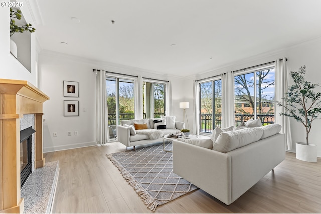 living room with a wealth of natural light, light hardwood / wood-style flooring, a high end fireplace, and ornamental molding