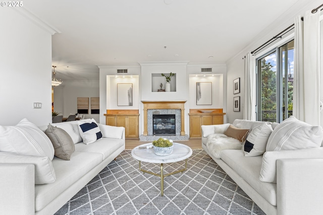 living room with a high end fireplace, wood-type flooring, and ornamental molding