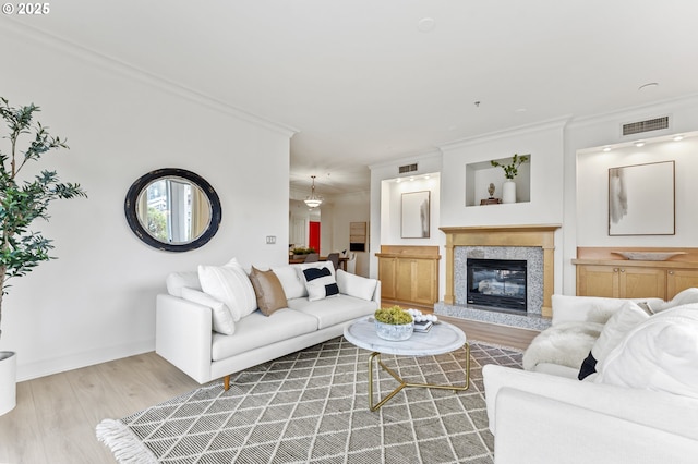 living room with a fireplace, light hardwood / wood-style flooring, and crown molding