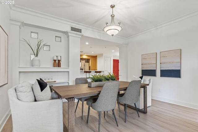 dining space with crown molding and light hardwood / wood-style flooring