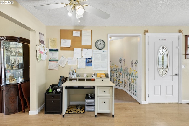 home office featuring a textured ceiling, a ceiling fan, light wood-style flooring, and baseboards