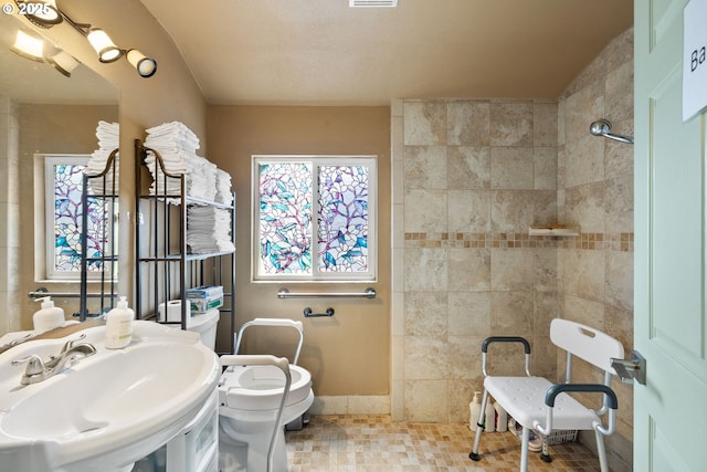 bathroom featuring a sink, toilet, tile patterned flooring, and tiled shower