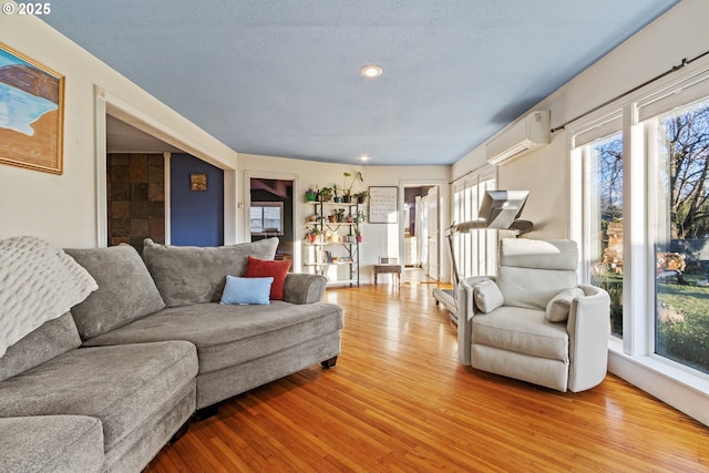 living room with light wood-style floors, recessed lighting, a textured ceiling, and a wall mounted AC