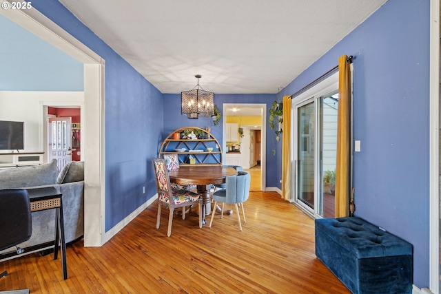 dining room featuring a notable chandelier, baseboards, and light wood-style floors