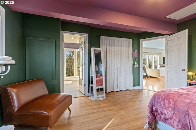 bedroom with baseboards, multiple windows, ensuite bathroom, and light wood-style floors