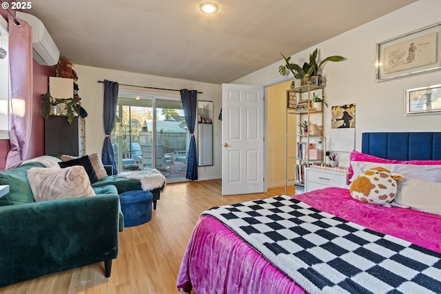 bedroom with an AC wall unit, light wood-style floors, and access to exterior