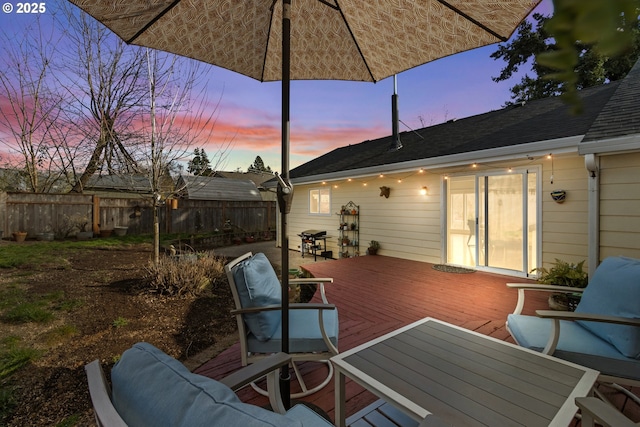 deck at dusk with area for grilling and fence