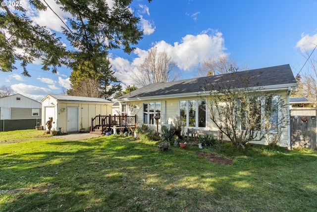 rear view of property featuring an outbuilding, a yard, fence, a deck, and a shed