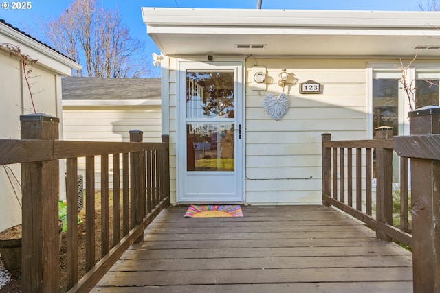 view of exterior entry with a deck and visible vents