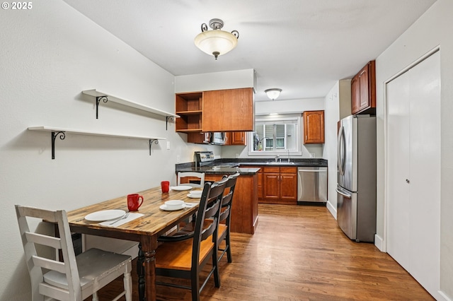 6610 SW Terri Ct Unit 10, Portland, OR 97225 - kitchen with stainless steel appliances, open shelves, dark countertops, brown cabinetry, and wood finished floors