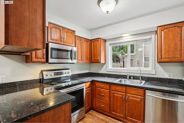 6610 SW Terri Ct Unit 10, Portland, OR 97225 - kitchen featuring stainless steel appliances, light wood finished floors, brown cabinetry, and dark stone countertops