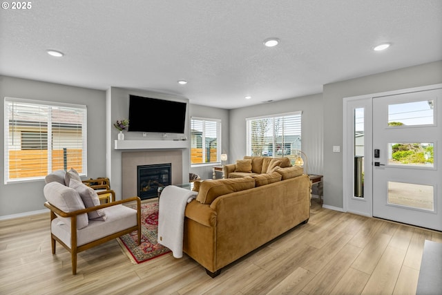 5820 El Mar Ave, Lincoln City, OR 97367 - living area featuring a textured ceiling, light wood-style floors, a glass covered fireplace, baseboards, and recessed lighting