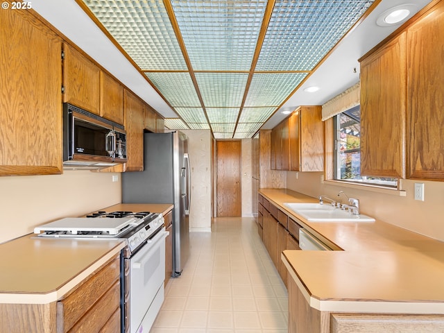 6002 E Evergreen Blvd, Vancouver, WA 98661 - kitchen featuring white gas range, stainless steel microwave, light countertops, brown cabinets, and a peninsula