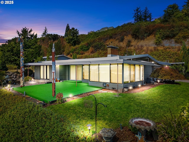 6002 E Evergreen Blvd, Vancouver, WA 98661 - rear view of property featuring a putting area, a lawn, a chimney, and a sunroom