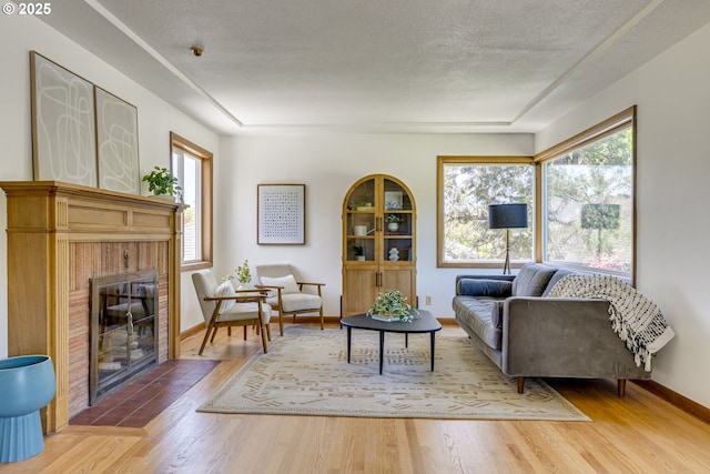 6220 SW 45th Ave, Portland, OR 97221 - living area with a fireplace, wood finished floors, baseboards, and a textured ceiling